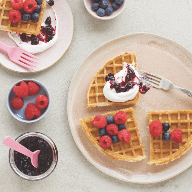Delicious waffles displayed on plates with berries and yogurt