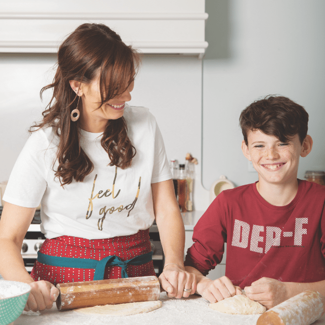 Mother and son laughing as they roll dough on granite countertop