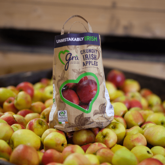 Gra apple bag sitting on bed of apples in retail store