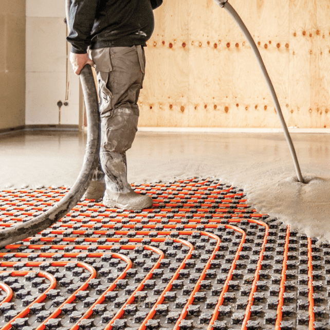 Man pouring concrete with orange pipe underlay