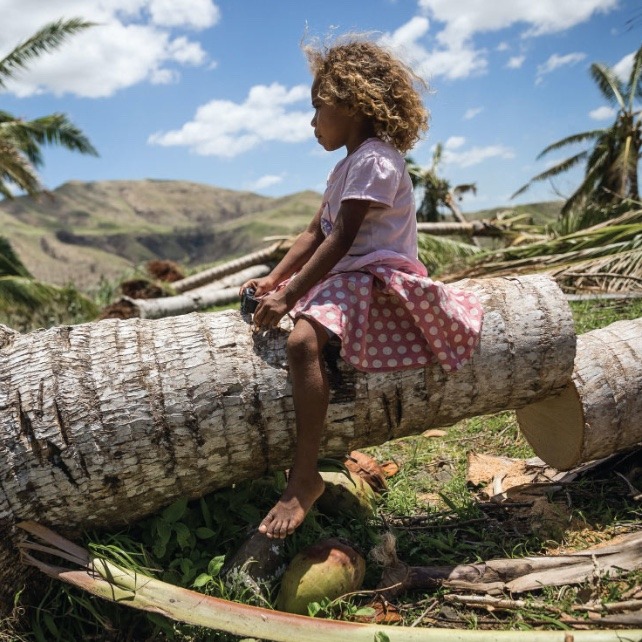 Image of girl sitting on tree trunk that has been chopped down