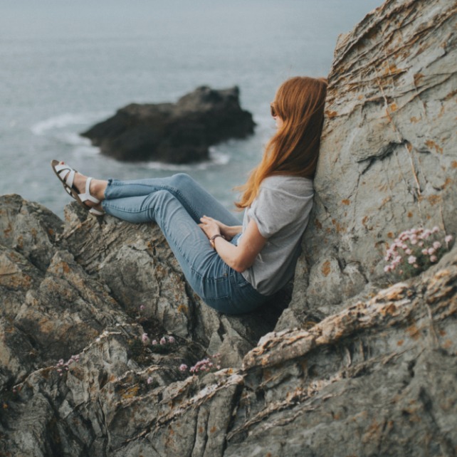 Image of woman sitting on cliffs at beach