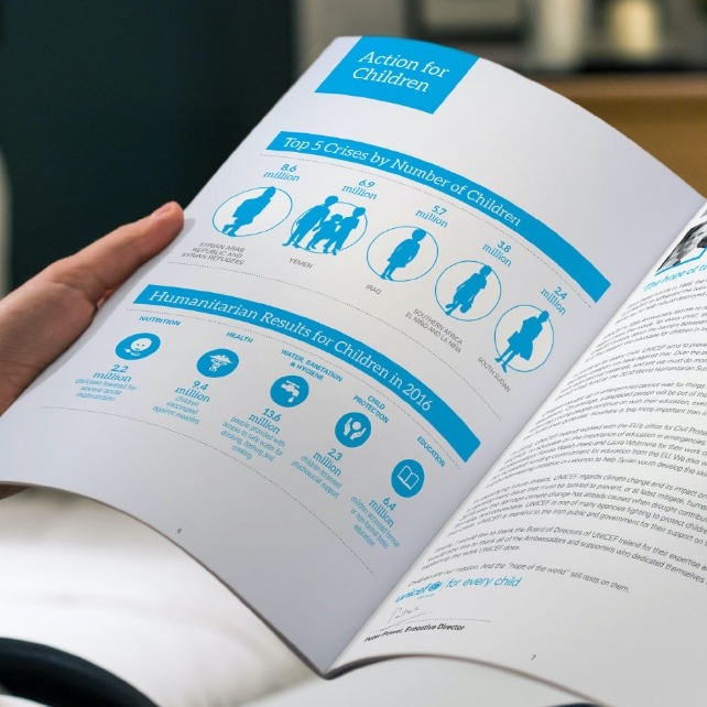 Person holding Unicef annual report spread design showcasing infographic